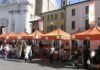 Mercato agricolo con bancarelle arancioni in Piazza Santa Maria a Montichiari.