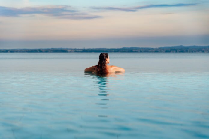 Donna rilassata in piscina a sfioro con vista sul lago di Garda a Desenzano