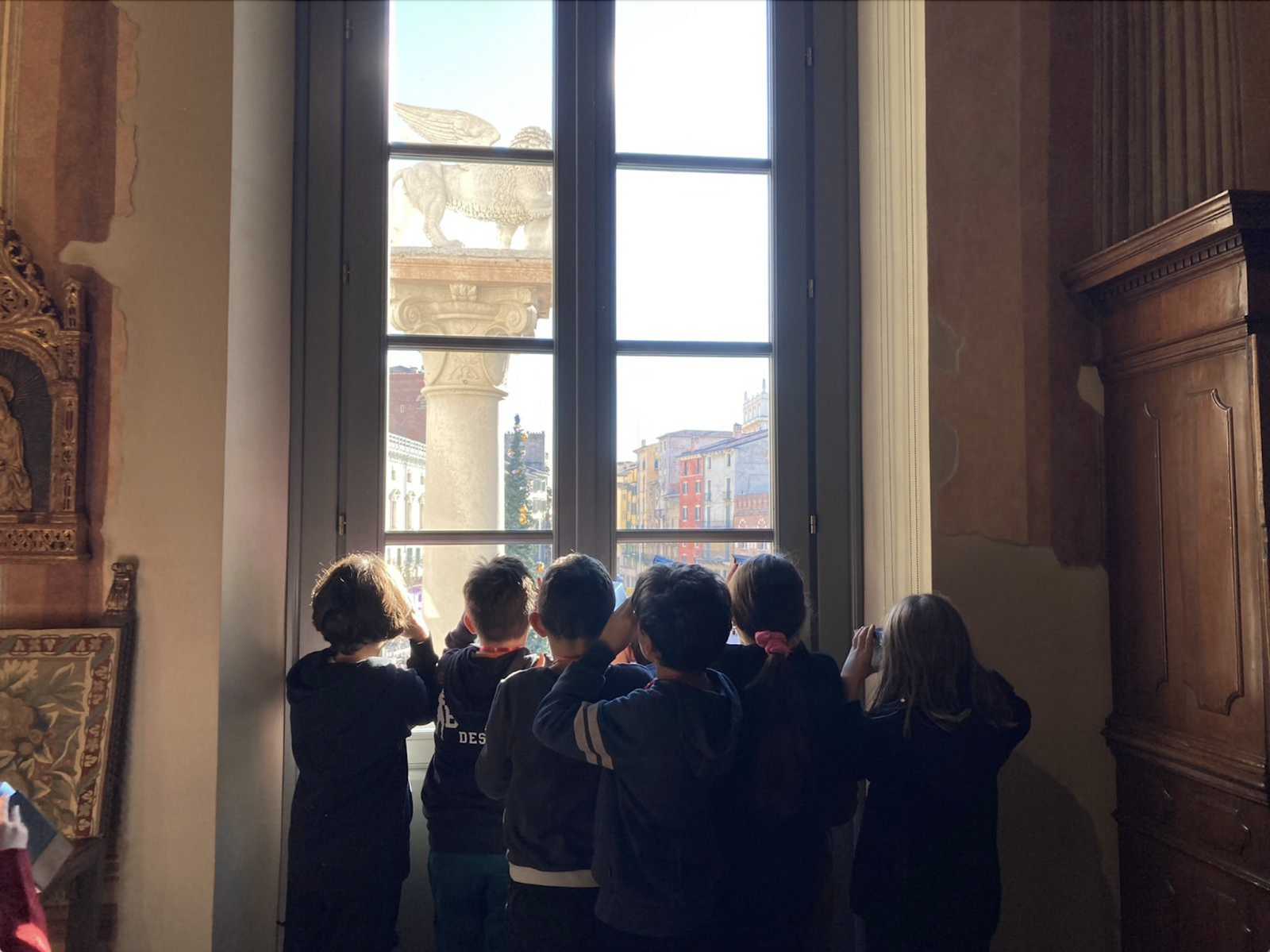 Studenti in visita guidata a Palazzo Maffei a Verona osservano il panorama.