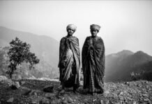 Due uomini nepalesi in abiti tradizionali con montagne sullo sfondo.