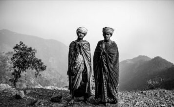 Due uomini nepalesi in abiti tradizionali con montagne sullo sfondo.