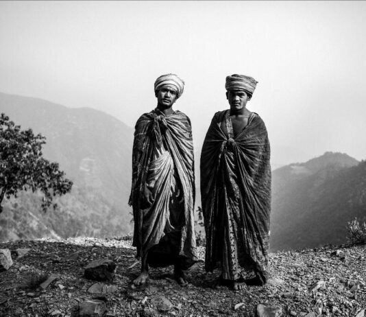 Due uomini nepalesi in abiti tradizionali con montagne sullo sfondo.