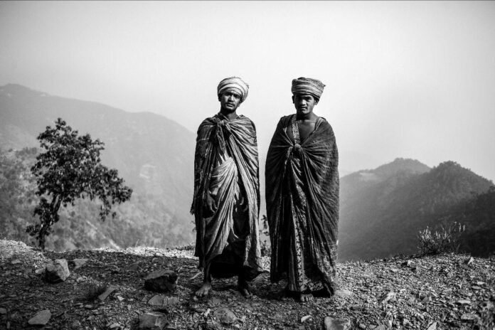 Due uomini nepalesi in abiti tradizionali con montagne sullo sfondo.
