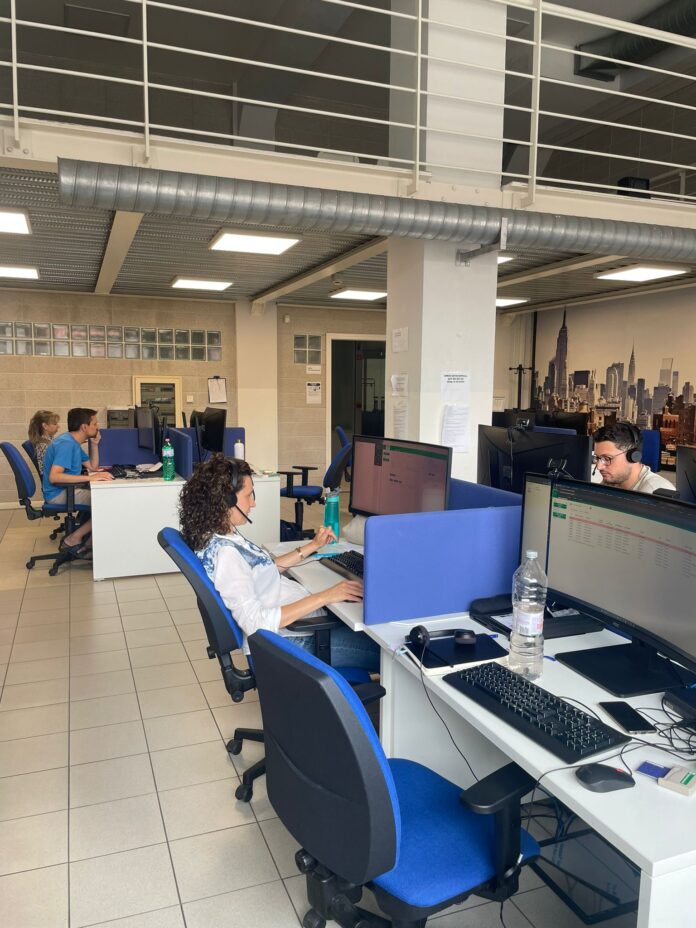Operatori della centrale assistenza Brescia al lavoro nelle postazioni telefoniche