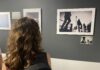 Una visitatrice osserva le fotografie esposte nella mostra WOUND | FERITA