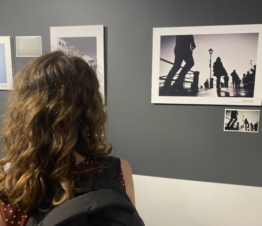 Una visitatrice osserva le fotografie esposte nella mostra WOUND | FERITA