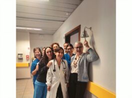 ASST Garda porta la Campanella del Sollievo nei Day Hospital di Desenzano, Manerbio e Gavardo Un gruppo di persone sorride in un corridoio di un ospedale mentre una donna in camice bianco tiene uno stetoscopio