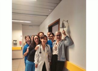 ASST Garda porta la Campanella del Sollievo nei Day Hospital di Desenzano, Manerbio e Gavardo Un gruppo di persone sorride in un corridoio di un ospedale mentre una donna in camice bianco tiene uno stetoscopio