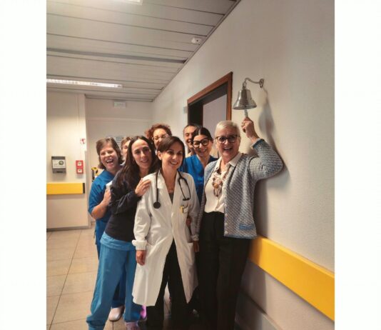 ASST Garda porta la Campanella del Sollievo nei Day Hospital di Desenzano, Manerbio e Gavardo Un gruppo di persone sorride in un corridoio di un ospedale mentre una donna in camice bianco tiene uno stetoscopio