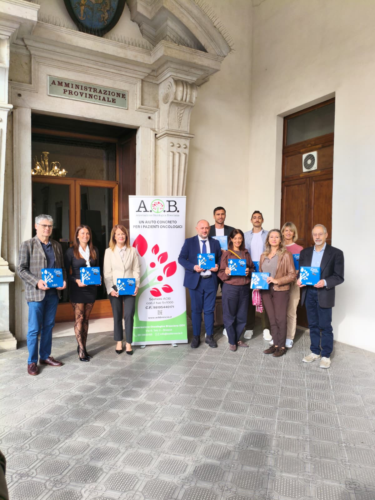 Un gruppo di persone tiene cioccolatini davanti al palazzo della Presidenza della Provincia di Brescia
