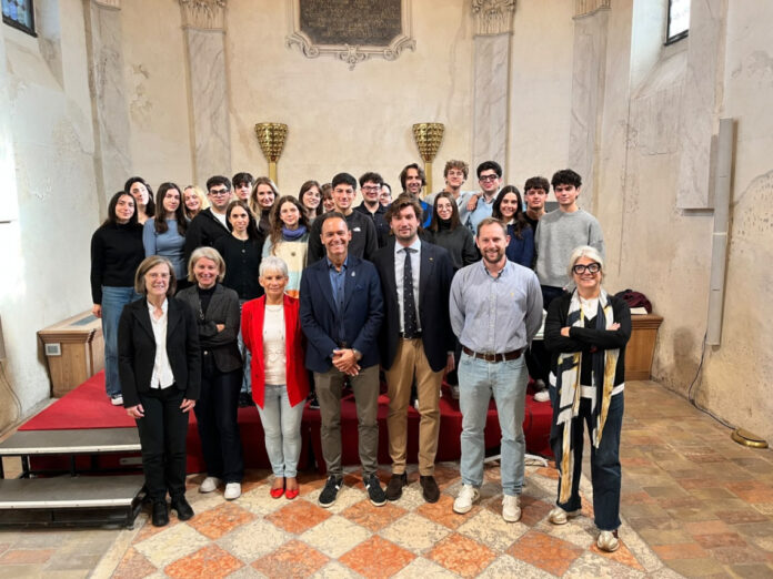 Un gruppo di giovani sorride in una sala antica davanti a un palco rosso