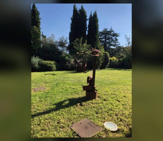 Scultura in un prato con alberi dietro