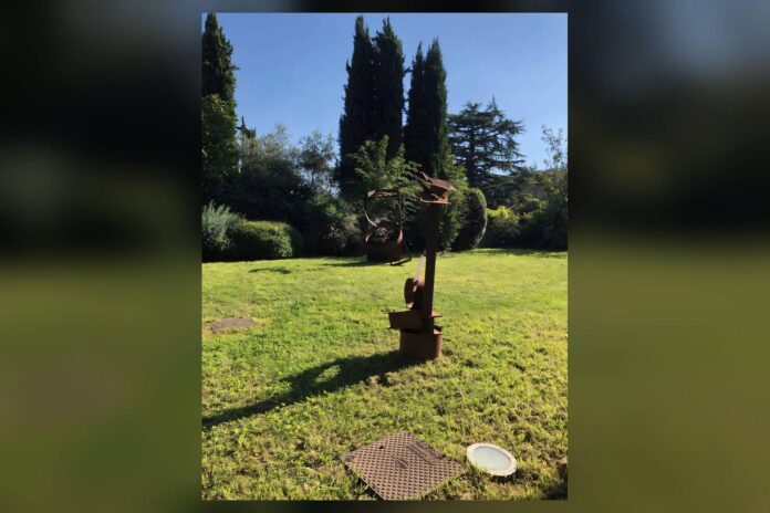 Scultura in un prato con alberi dietro
