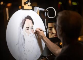 Un artista disegna un ritratto su un supporto illuminato in Riva del Garda durante una serata