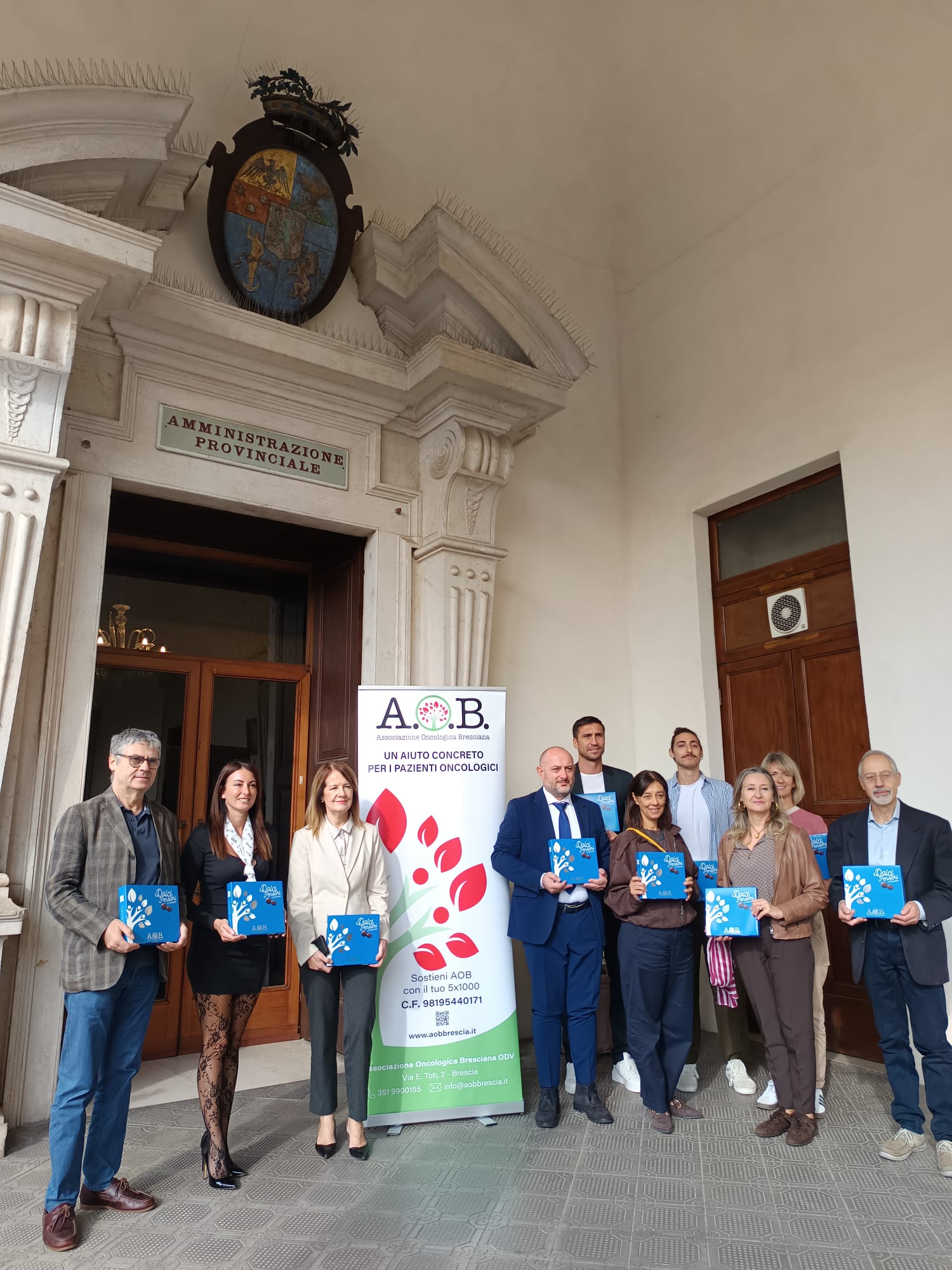 Un gruppo di persone tiene in mano cioccolatini davanti al palazzo della Presidenza della Provincia di Brescia