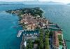 Vista aerea della penisola di Sirmione sul lago di Garda, con il centro storico tra alberi e acqua