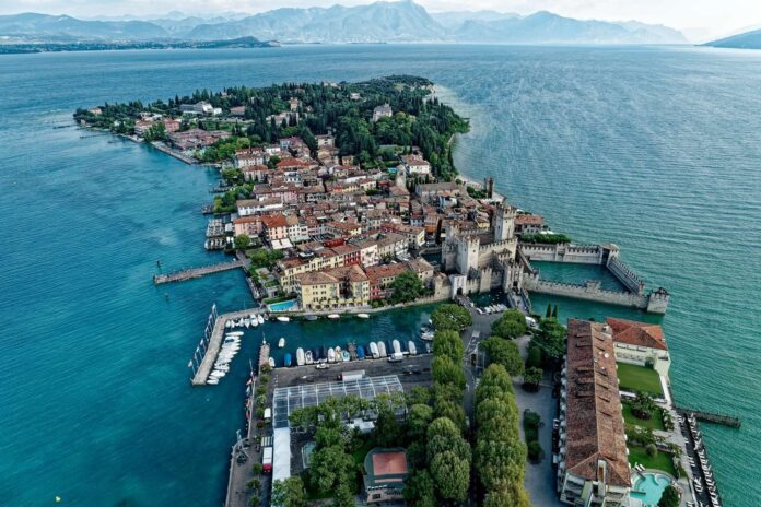 Vista aerea della penisola di Sirmione sul lago di Garda, con il centro storico tra alberi e acqua