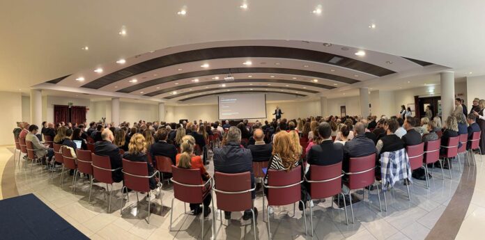 Sala affollata con persone sedute davanti a una parete bianca per il Lake Garda Hospitality Summit a Peschiera del Garda