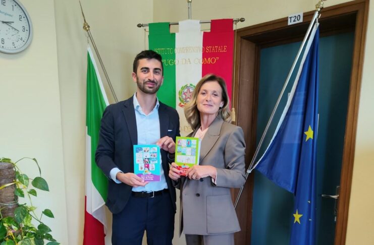 Uomini e donne in aula mostrano libri accanto a bandiere e finestre