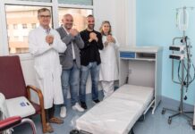 Quattro persone sorridono in una stanza con letti e apparecchiature mediche presso il reparto di Oncologia degli Spedali Civi