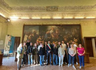 Un gruppo di giovani in sala con un grande dipinto sullo sfondo