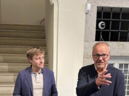 Renzo Troglio espone al Museo Lechi di Montichiari fino all’8 novembre Due persone in abiti diversi stanno in piedi in un ambiente interno con una scala di legno alle loro spalle.