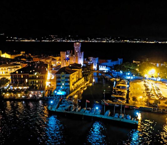 Sirmione di notte, con gli edifici illuminati e le barche lungo la riva