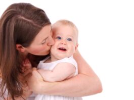Una donna abbraccia un bambino sorridente in un ambiente bianco
